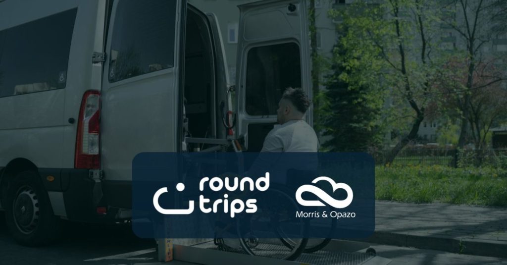 White accessibility van with open side doors and a wheelchair user entering, overlaid with Round Trips and Morris & Opazo logos on a blue panel.